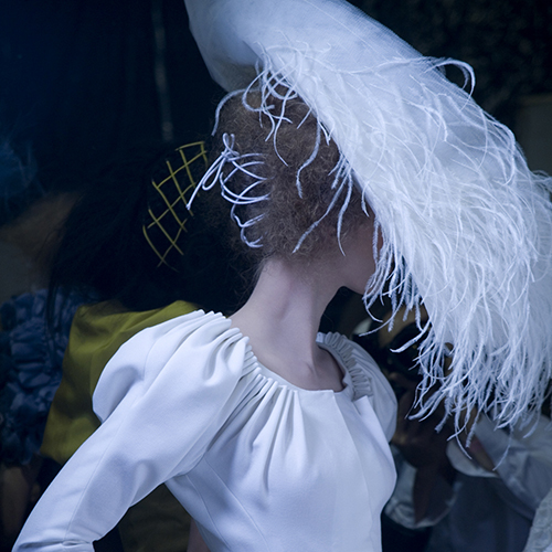 Modelo vestida de blanco con sombrero de plumas blancas