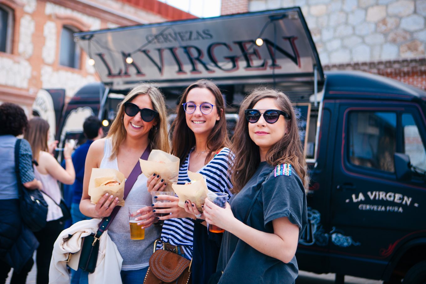 Mujeres con comida y bebida posando delante de food truck