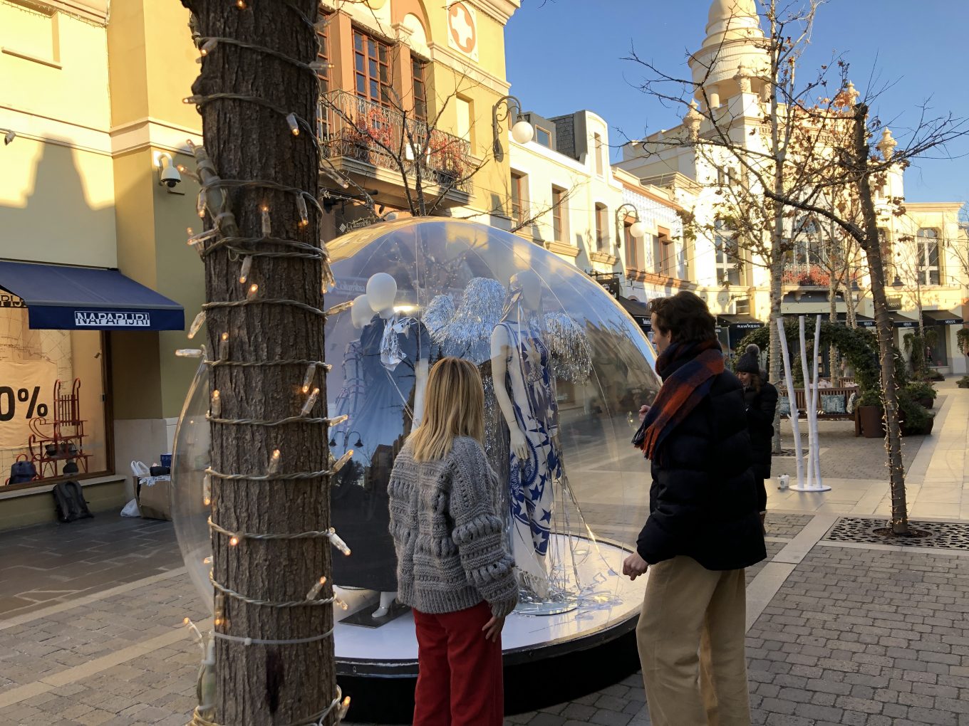 Peatones observan globo de cristal con maniquíes en su interior