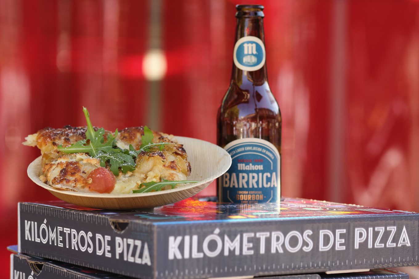 Plato con pizza sobre cajas de pizza con botellín de cerveza