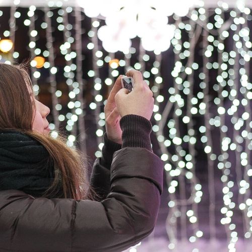 Mujer con abrigo y bufanda sujetando camara de fotos