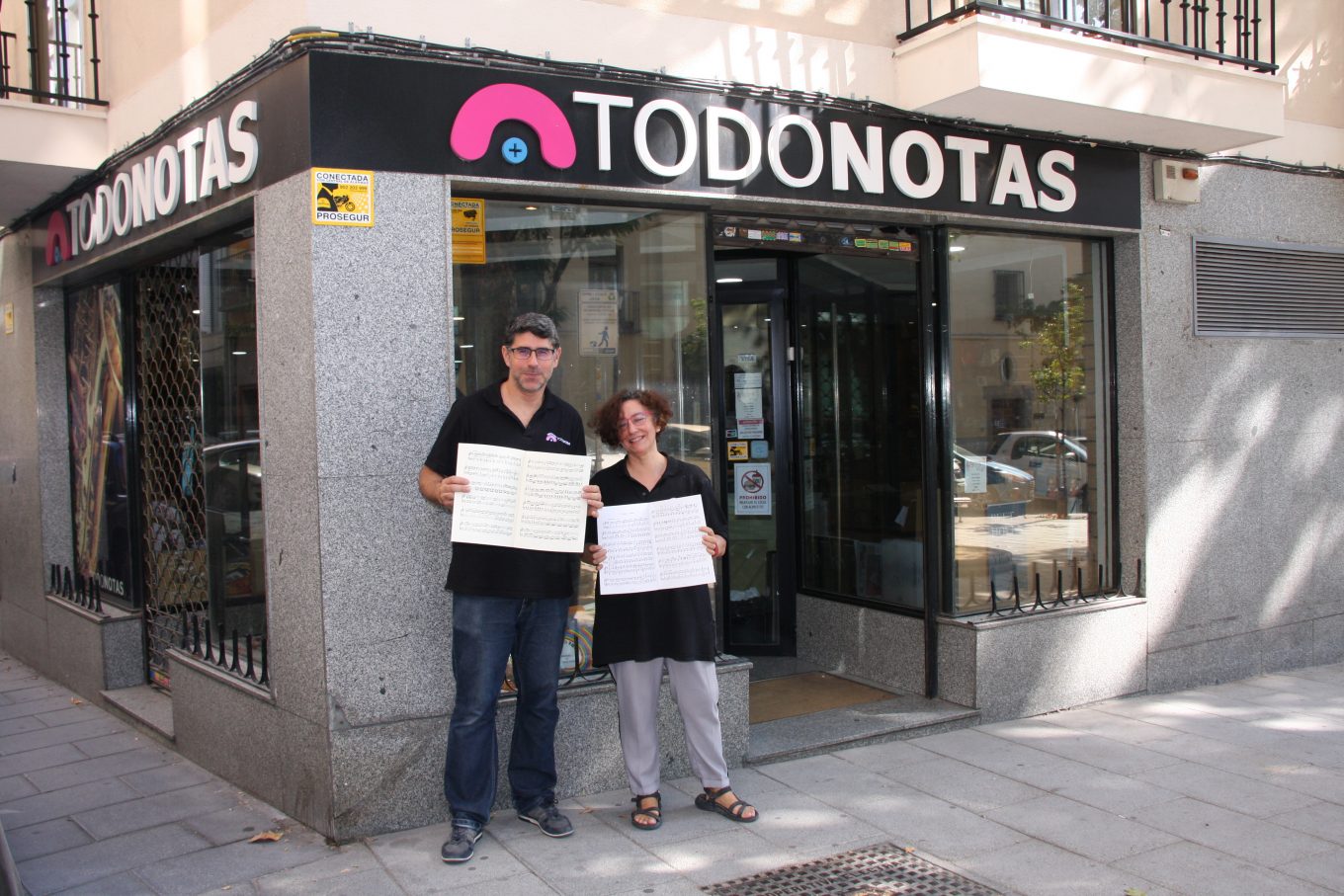 Hombre y mujer sujetando carteles delante de tienda de papelería