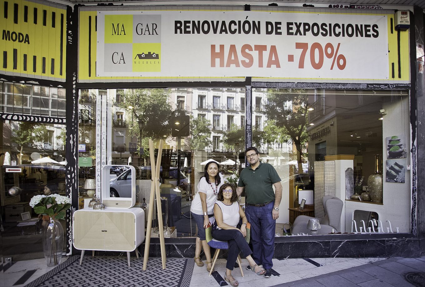 Dos mujeres y un hombre posando delante de tienda de muebles