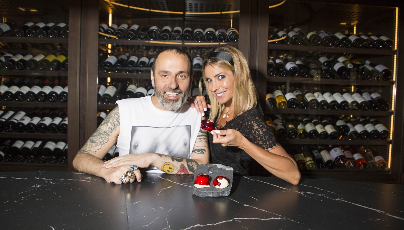 Hombre y mujer posando en bodega mostrando tapa gourmet