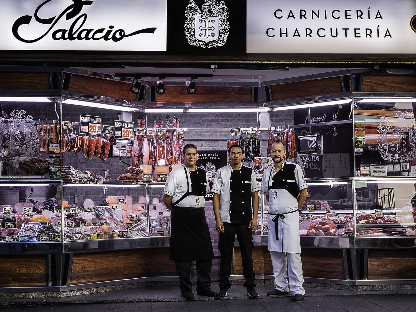 Hombres posando delante de puesto de charcutería