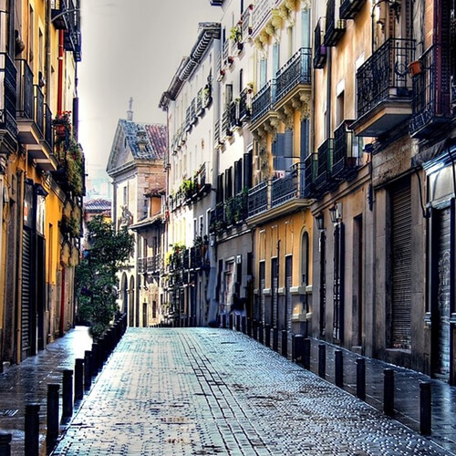 Calle con suelo mojado y desierta en barrio de las letras