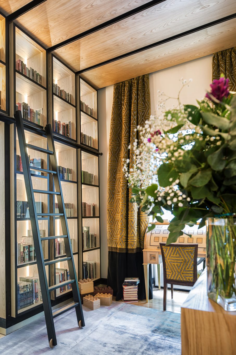 Biblioteca con escalera y florero en primer plano