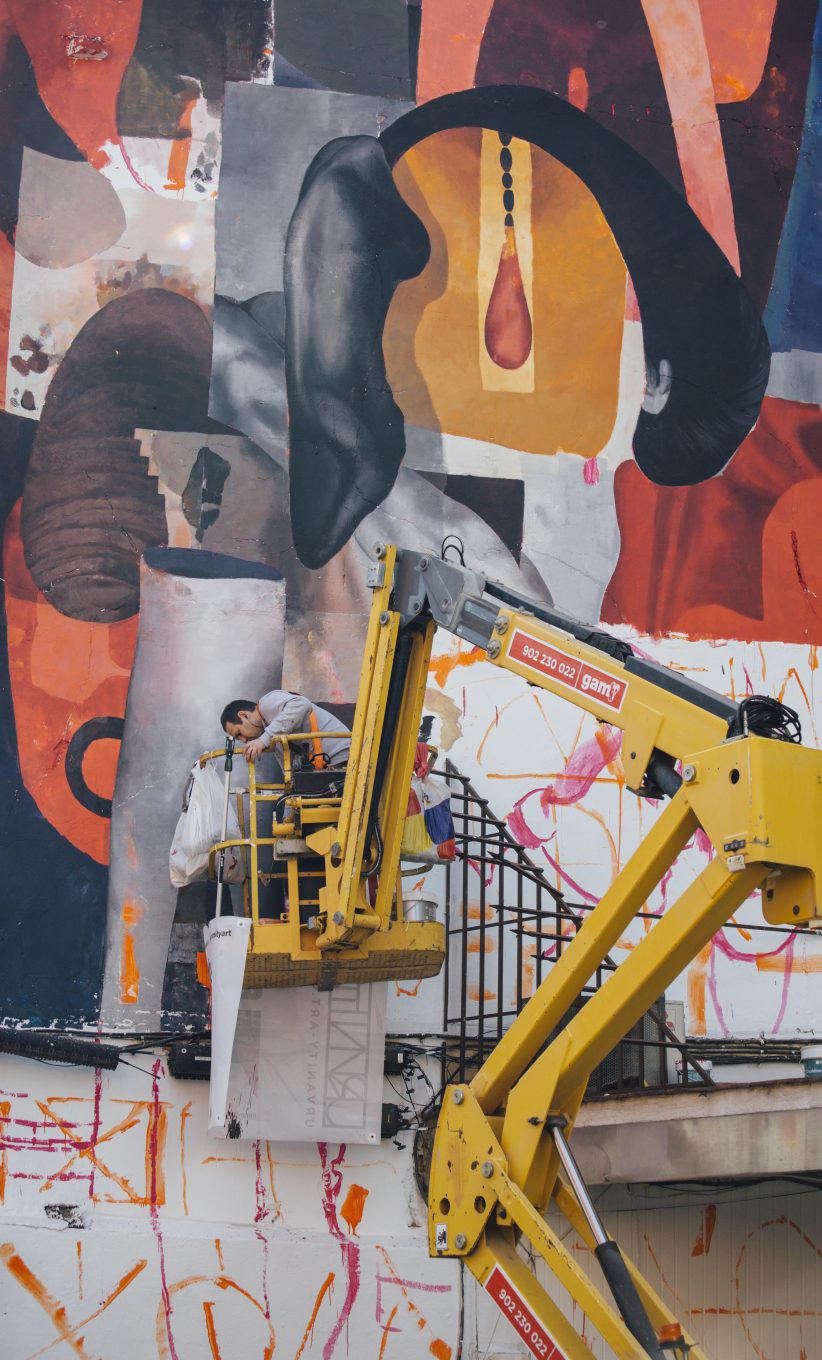 Operario pintando mural en fachada de edificio