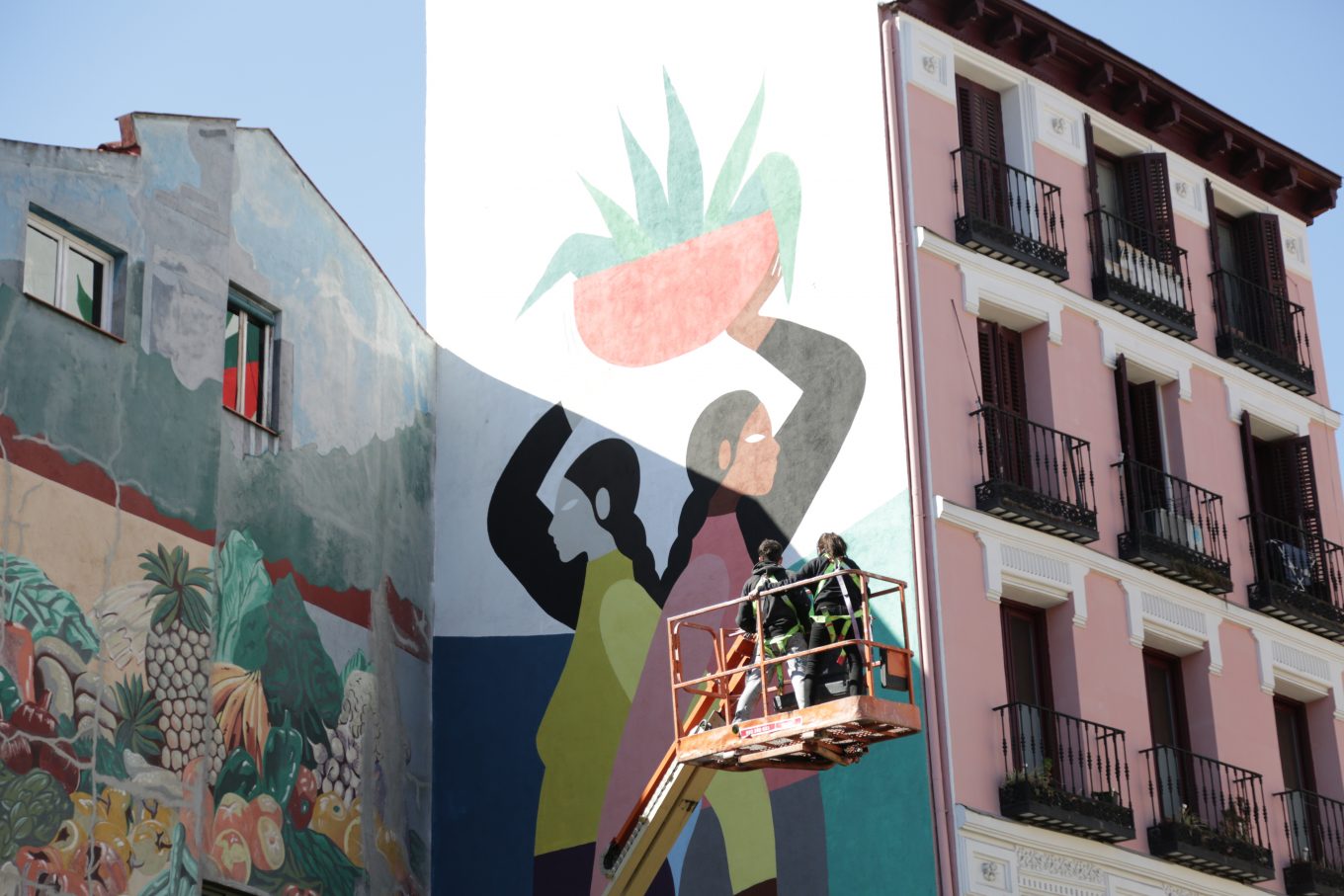 Operarios pintando mural en fachada de edificio