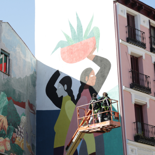 Operarios pintando mural en fachada de edificio