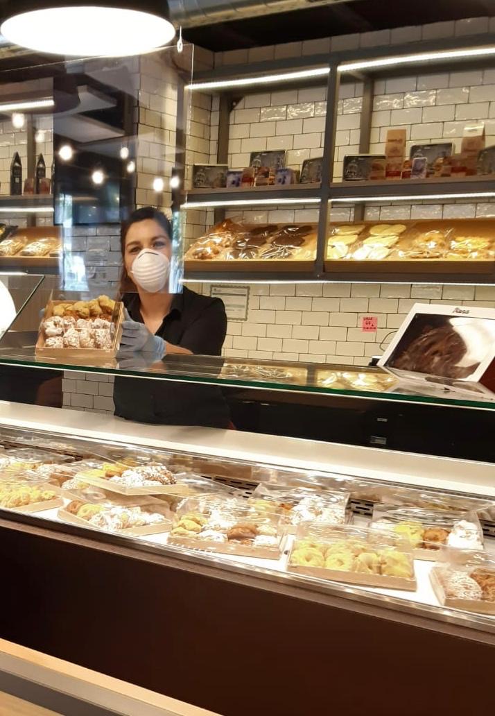 Mujer mirando a cámara detrás de expositor de productos de repostería