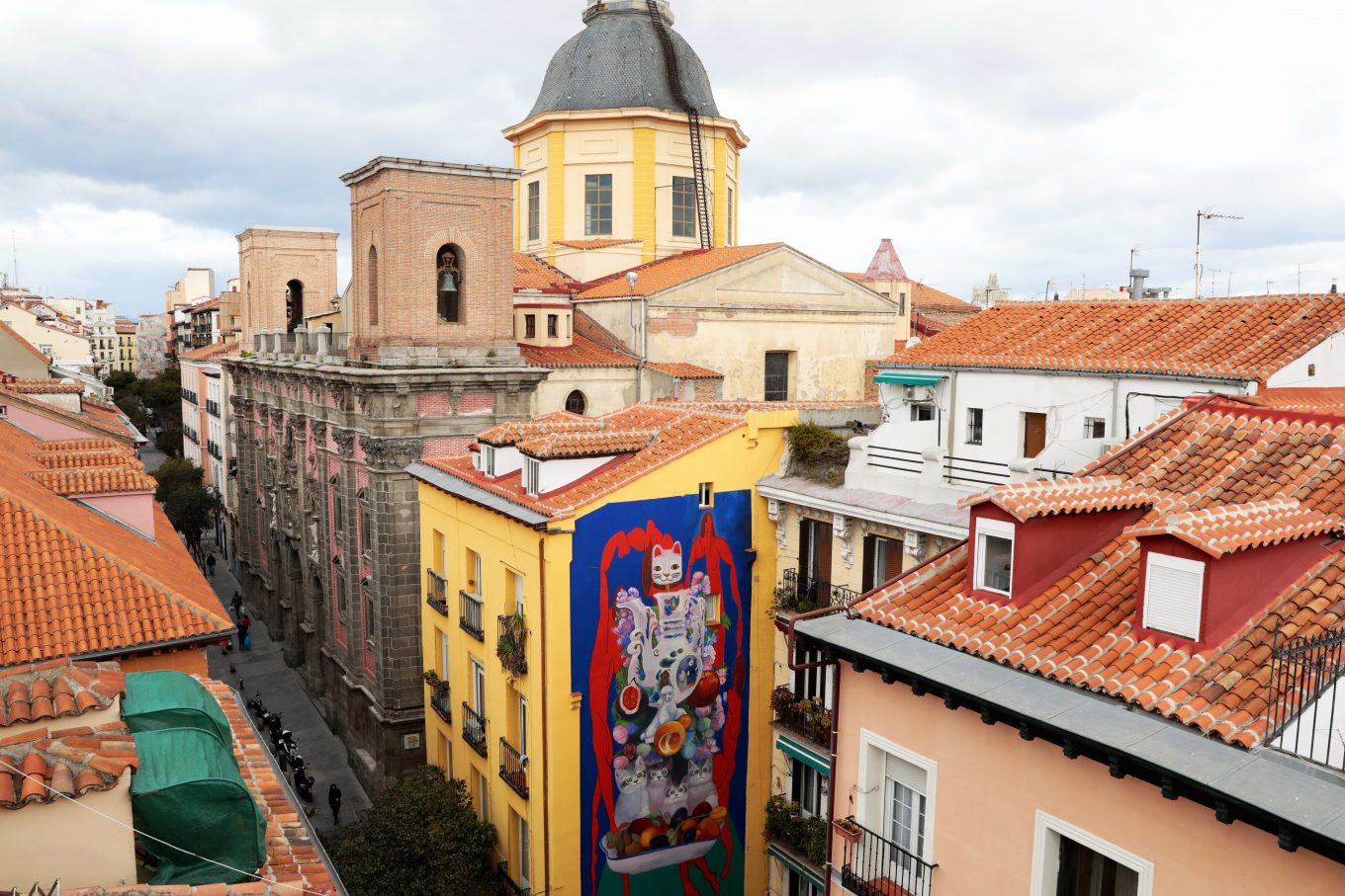 Vista de tejados con mural de gatos en fachada de edificio