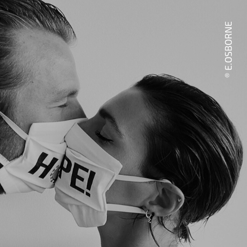 Hombre y mujer con mascarillas de tela besandose