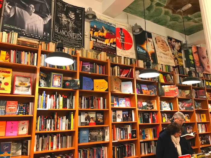 Personas consultando libros en interior de librería con estantes