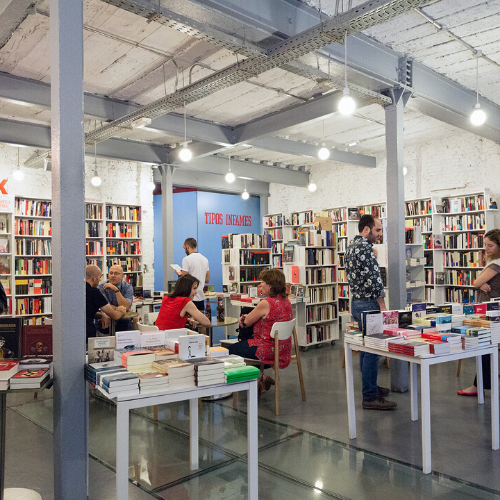 Interior de librería con gente, estanterías y expositor