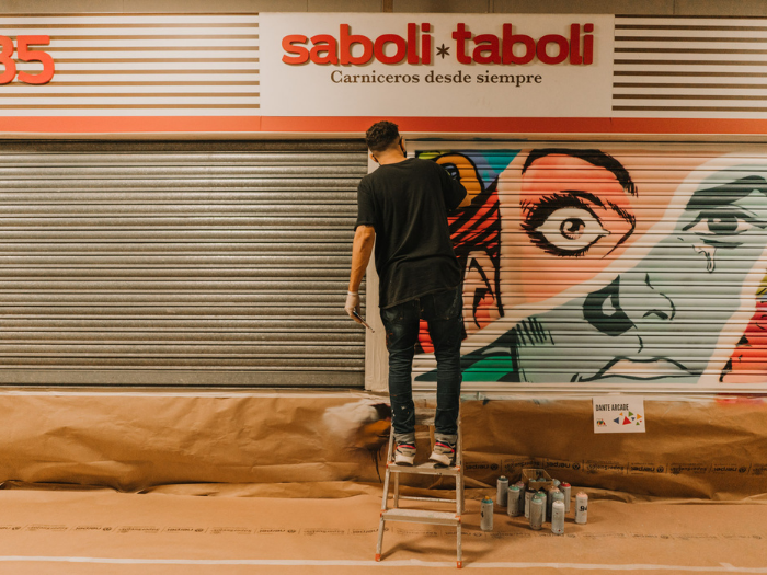El artista Dante Arcade pinta su mural en el mercado de los Mostenses