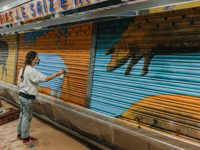 El artista Jimena At pinta un cierre de un puesto del mercado de Los Mostenses