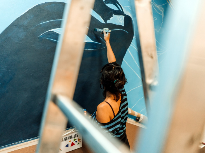 La artista Laura Gonballes con su mural en el mercado de los Mostenses