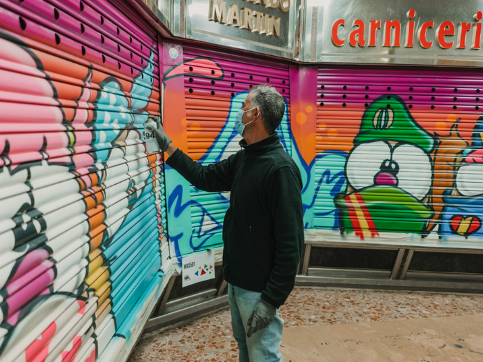 El artista Maz 501 pinta un cierre de un puesto del mercado de Los Mostenses