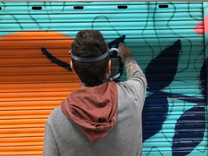 El artista De Tripas Aerosol pinta un cierre de un puesto del mercado de Los Mostenses