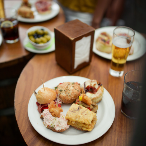 Mesa con un plato de tapas y cervezas