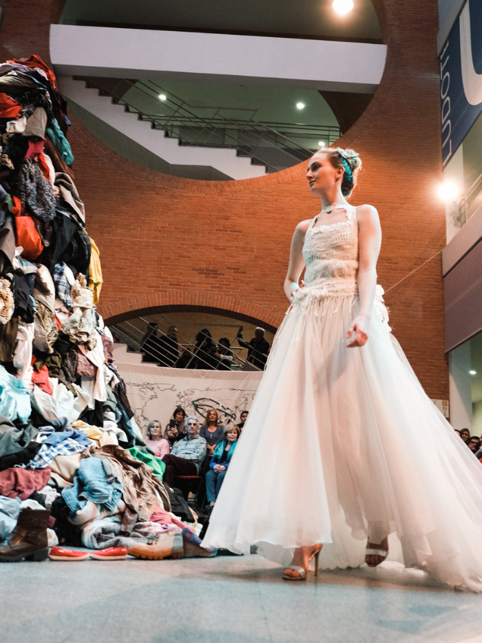 Mujer vestida de blanco observa un montón de ropa