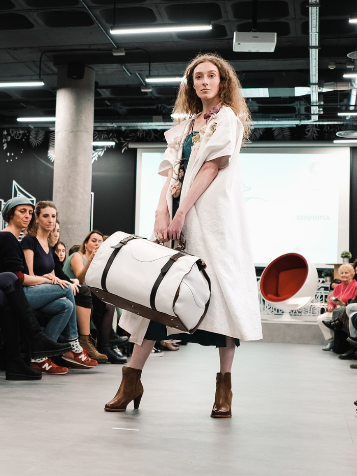 Mujer vestida de blanco con bolsa de viaje blanca