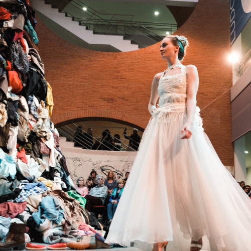 Mujer vestida de blanco observa un montón de ropa