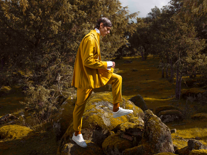 Hombre vestido con un traje mostaza en un bosque