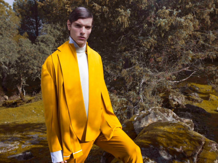 Hombre vestido con traje mostaza en un bosque