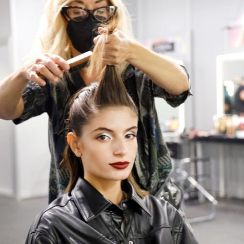 Una peluquera peina a una modelo en el backstage de MBFW Madrid