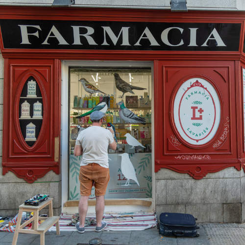 Artista creando su obra plástica en las paredes de un comercio de Lavapiés