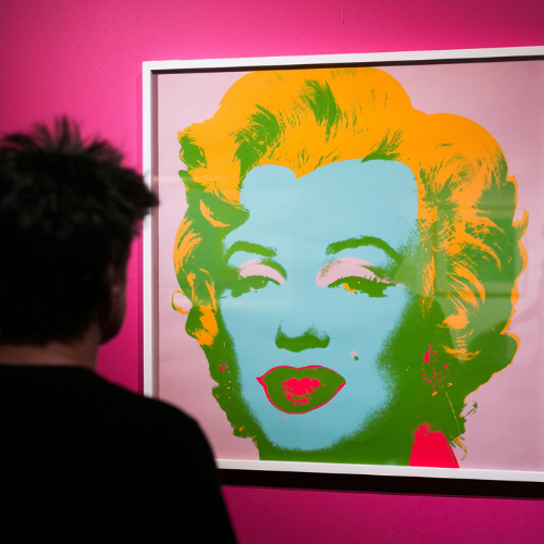 Una mujer observa el retrato de Marilyn Monroe hecho por Andy Warhol