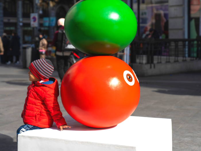 Niño junto a una estátua de arte contemporáneo en la calle Montera